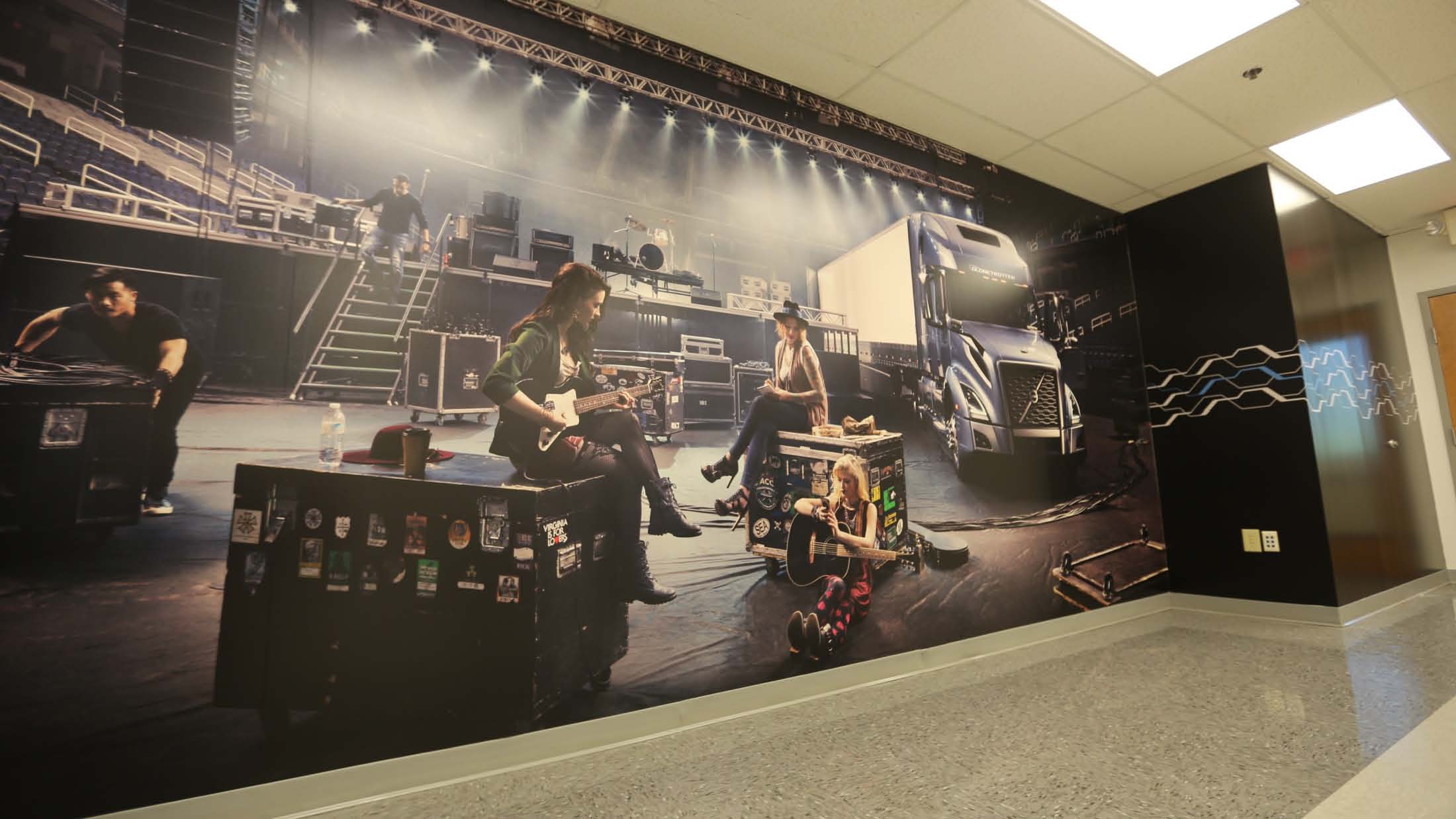 A large scale wall wrap for Volvo Mack in Atlanta, Georgia, showcasing a Volvo truck nearby a stage with a practicing band.