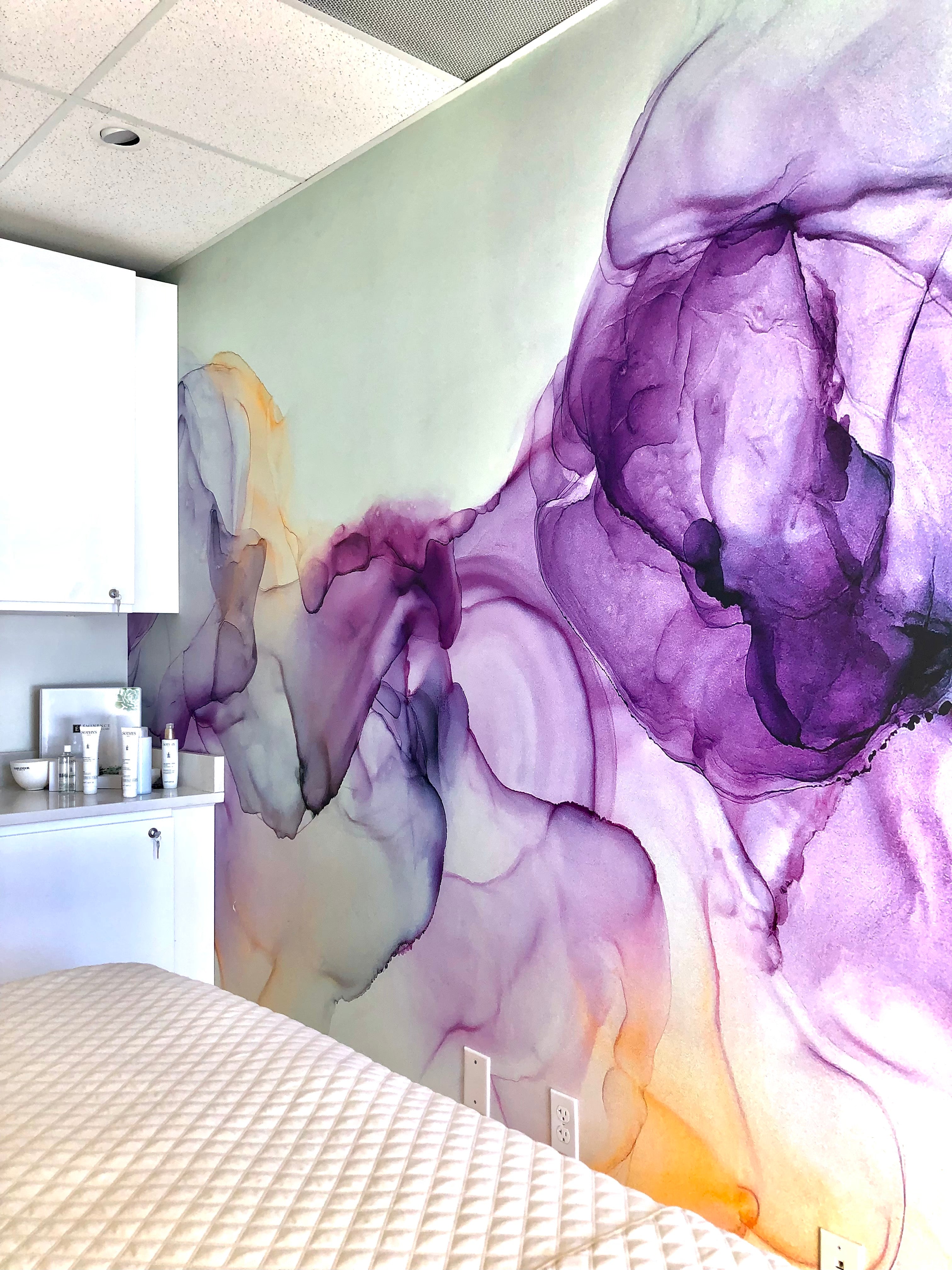 A beautifully designed wall wrap featuring fluid, watercolor-like swirls of purple and orange hues, installed in a treatment room at The Body Bar in Boulder, Colorado. The artwork adds a calming and sophisticated ambiance to the space.