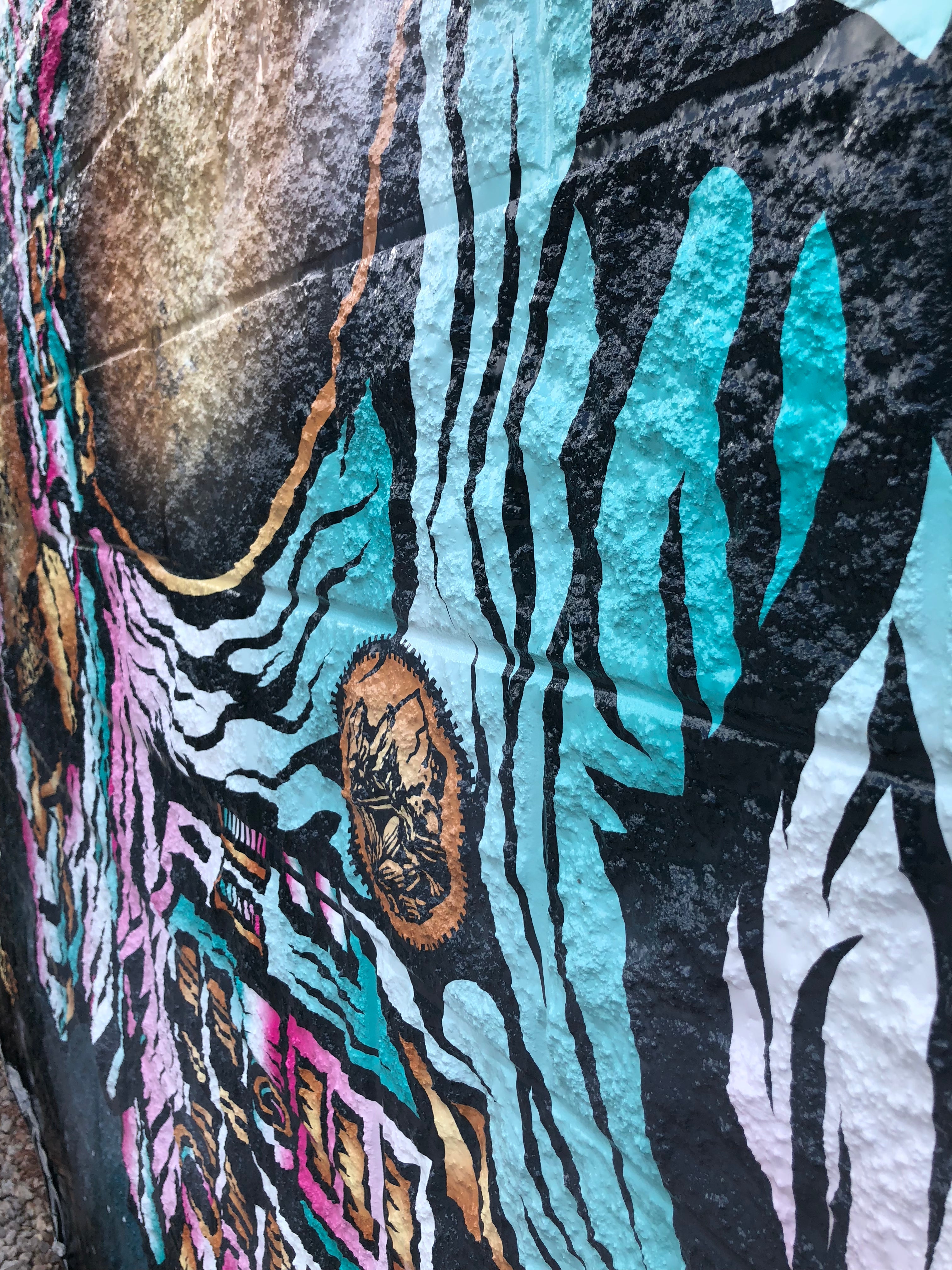 A close-up view of a building wrap on a brick and mortar surface, showcasing the high-quality vinyl designed to adhere effectively to textured surfaces. The vibrant artwork is part of a custom building wrap project for a brewery located in Boulder, Colorado.