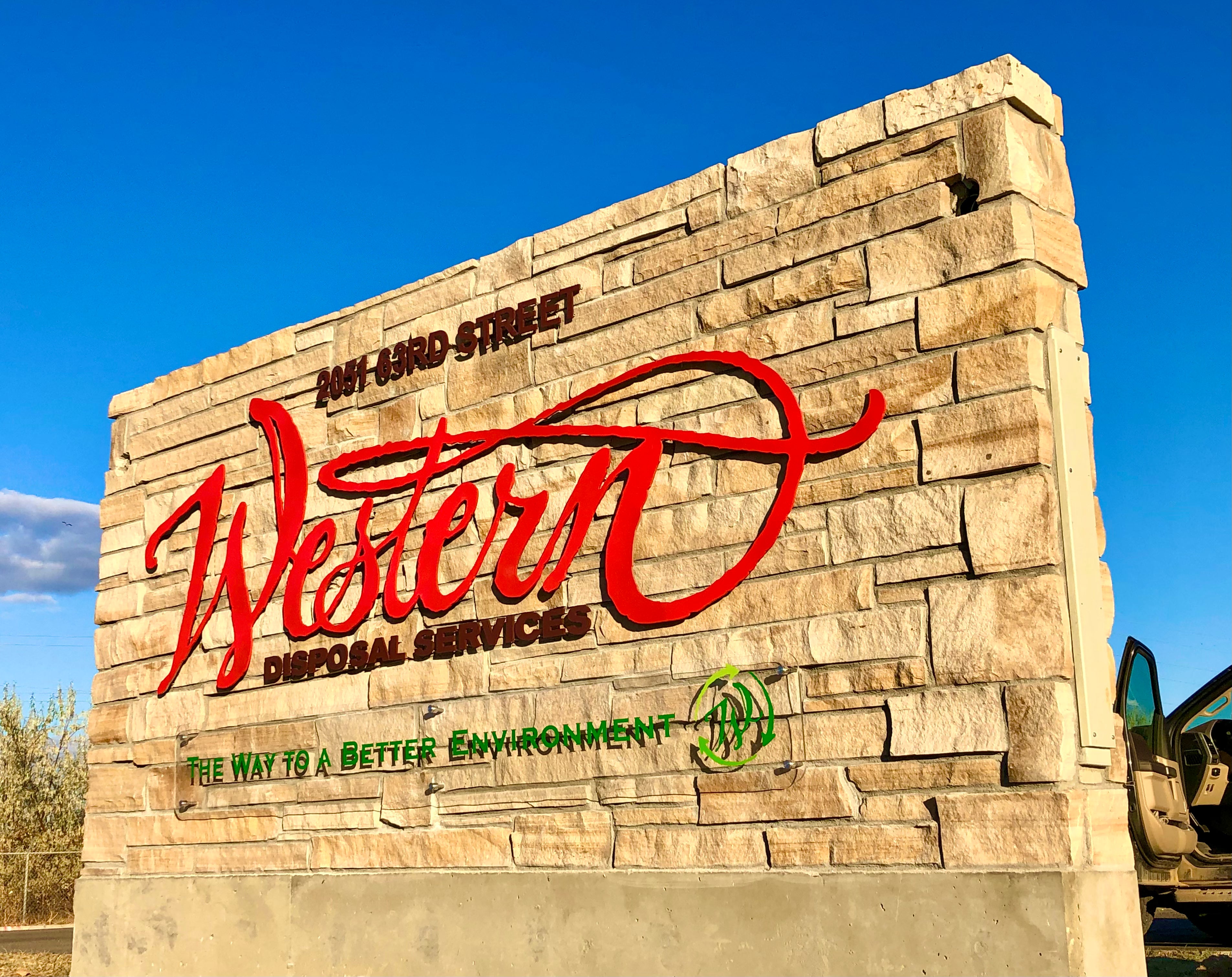 Monument sign for Western Disposal Services in Boulder, Colorado, with their logo in bright red and their motto of "The way to a better environment" in a dark green to show their commitment to the environment.