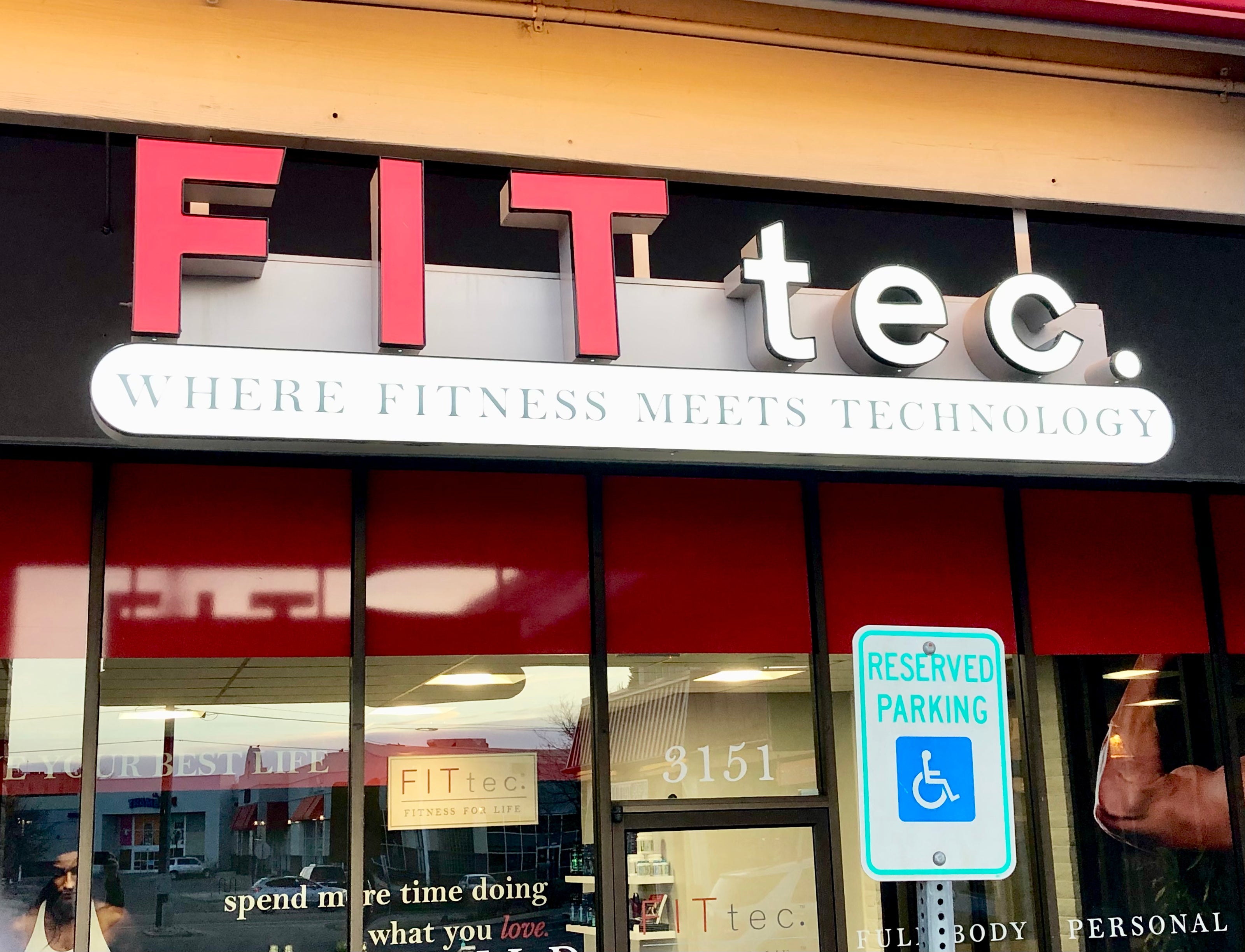 An outdoor sign for Fit tec. in Boulder, Colorado. Featuring their name in bright red and their slogan of "Where fitness meets technology" typed underneath on an illuminated white background to grab the attention of anyone.