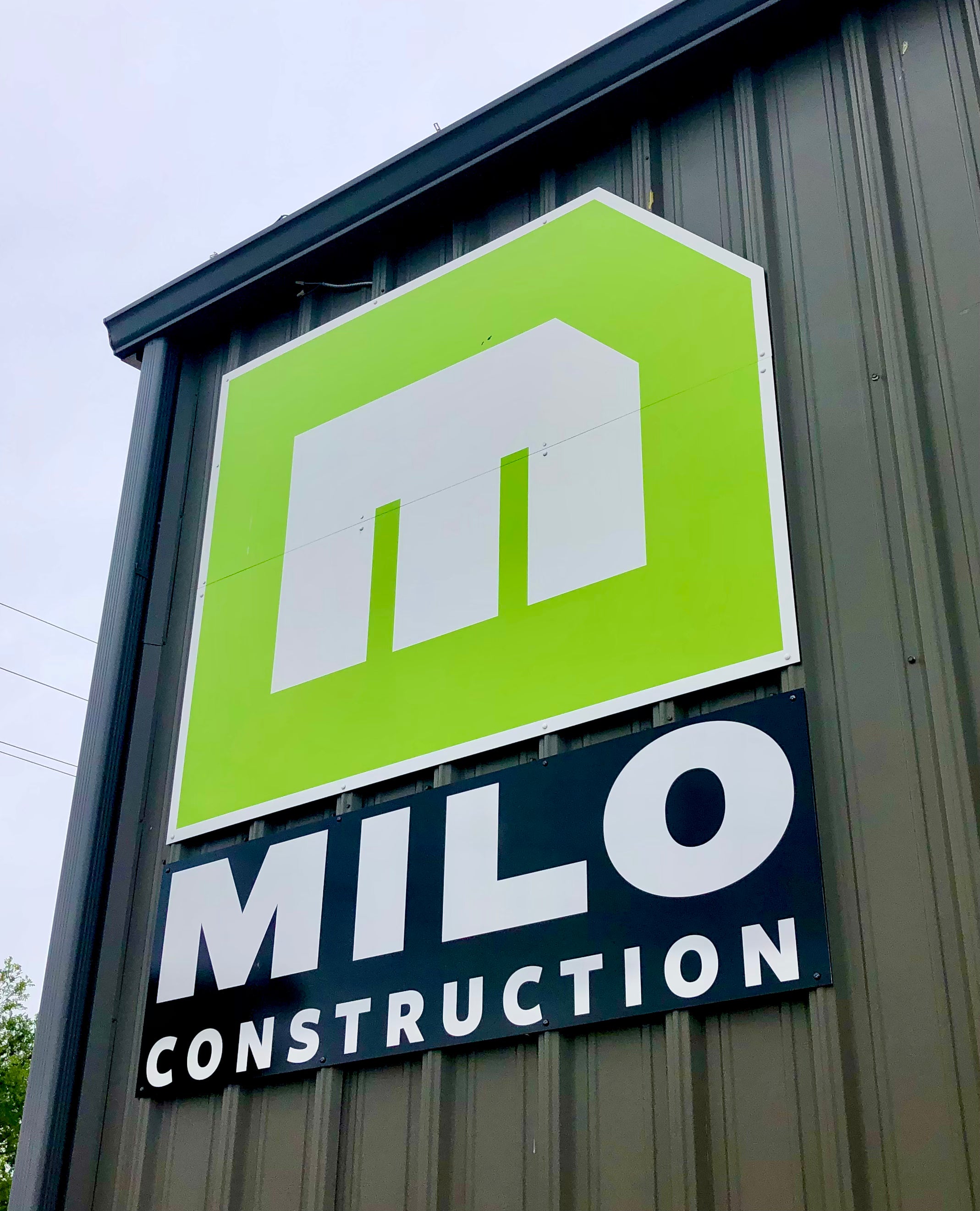 A panel sign for Milo Construction in Boulder, Colorado, with their icon lime green on full display to the world around them.