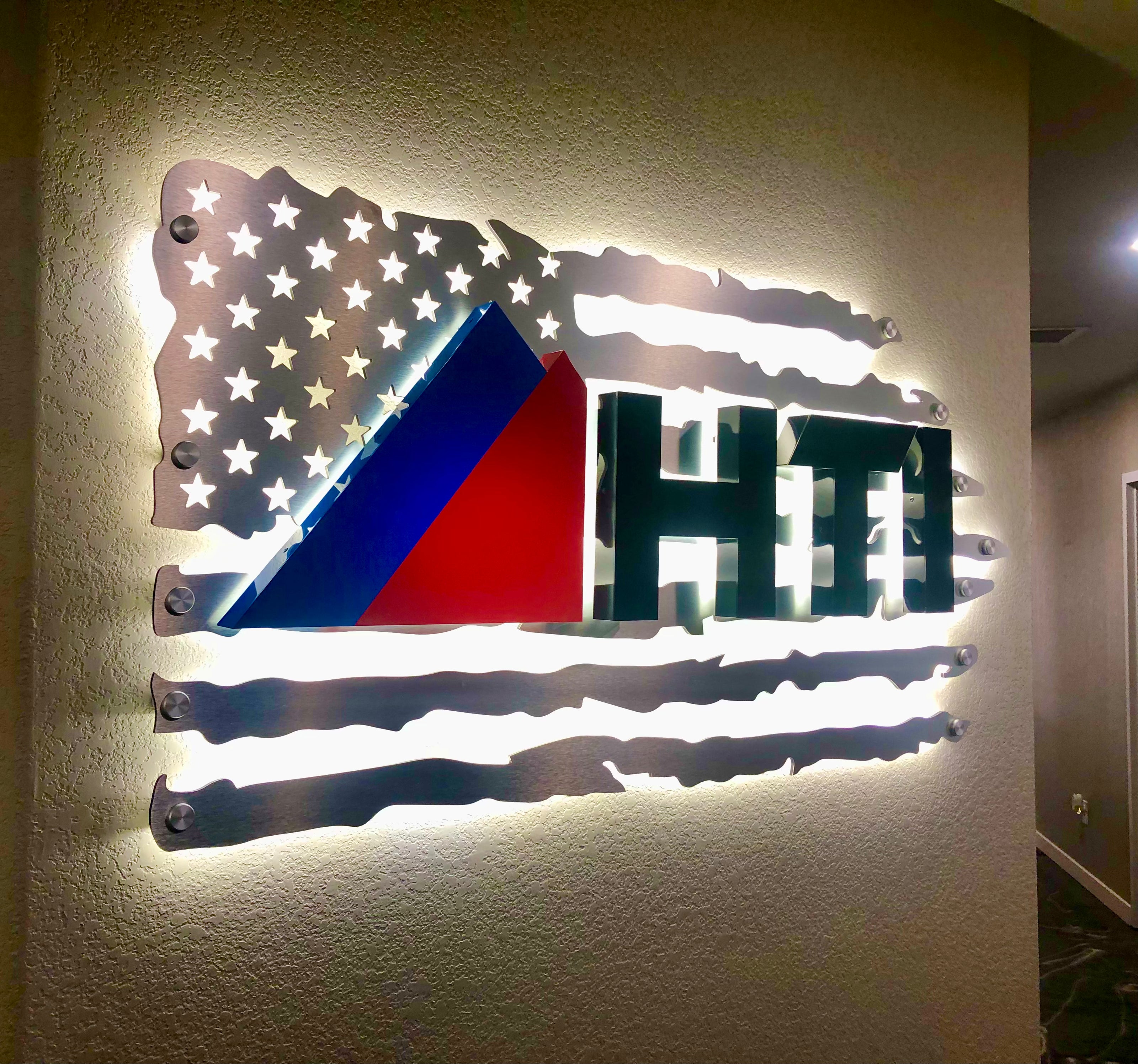 Illuminated wall sign for HTI (Heat Tech Industrial) in Frederick, Colorado. Featuring a modern design that enhances brand visibility, all on an American flag background, taking pride in their "Made in America" status.