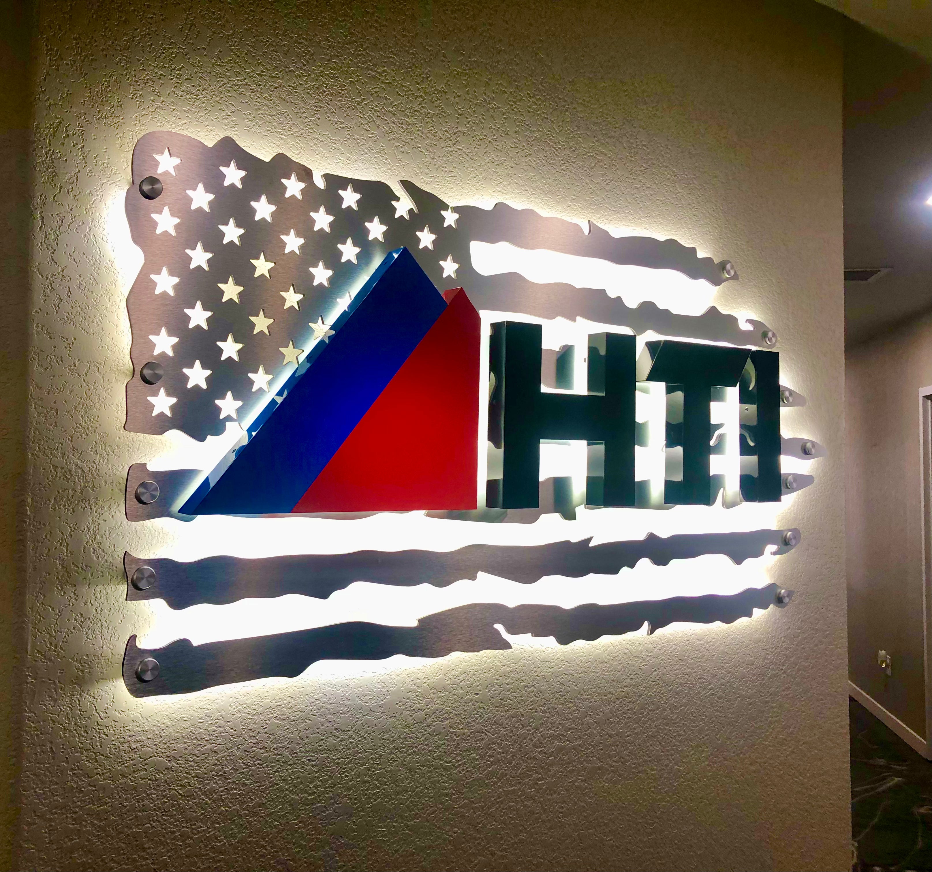 Illuminated wall sign for HTI (Heat Tech Industrial) in Frederick, Colorado. Featuring a modern design that enhances brand visibility, all on an American flag background, taking pride in their "Made in America" status.