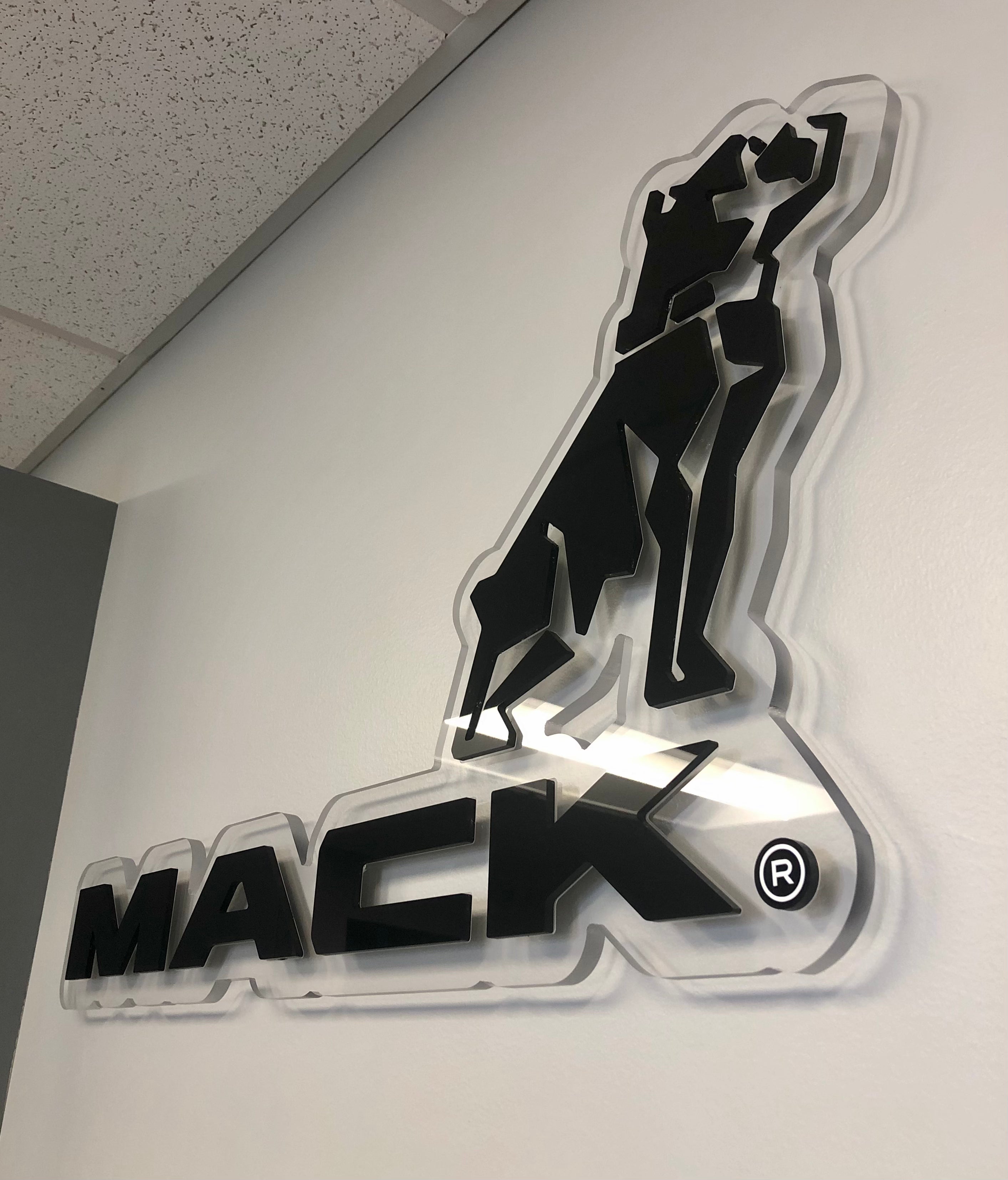 A black acrylic lobby sign on top of a clear acrylic background for Mack Trucks at their El Paso, Texas location.
