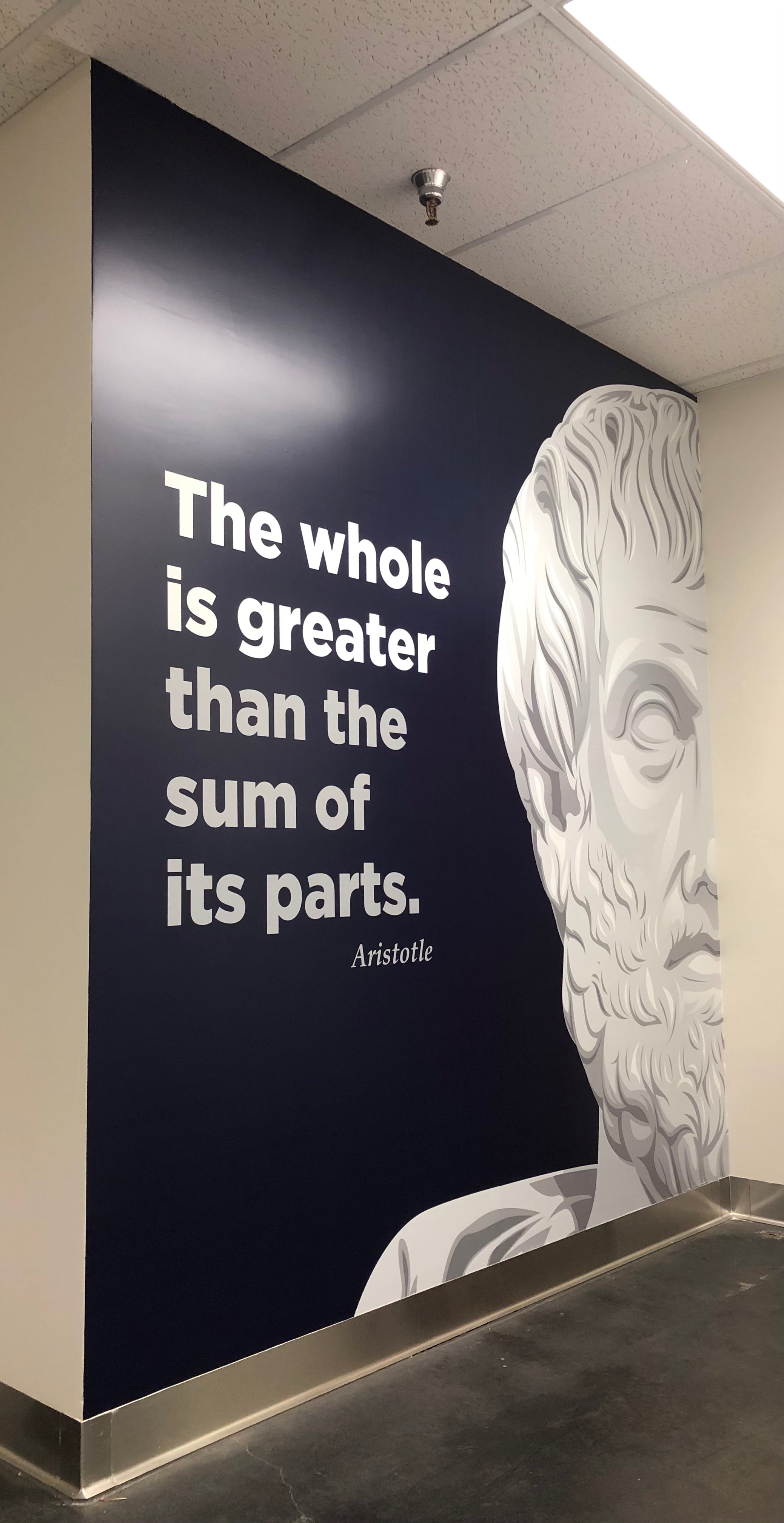 A simple, yet powerful wall wrap with a drawing of Aristotle as a statue with his famous quote, "The whole is greater than the sum of its parts," for LTM Plastic's office in Denver, Colorado.