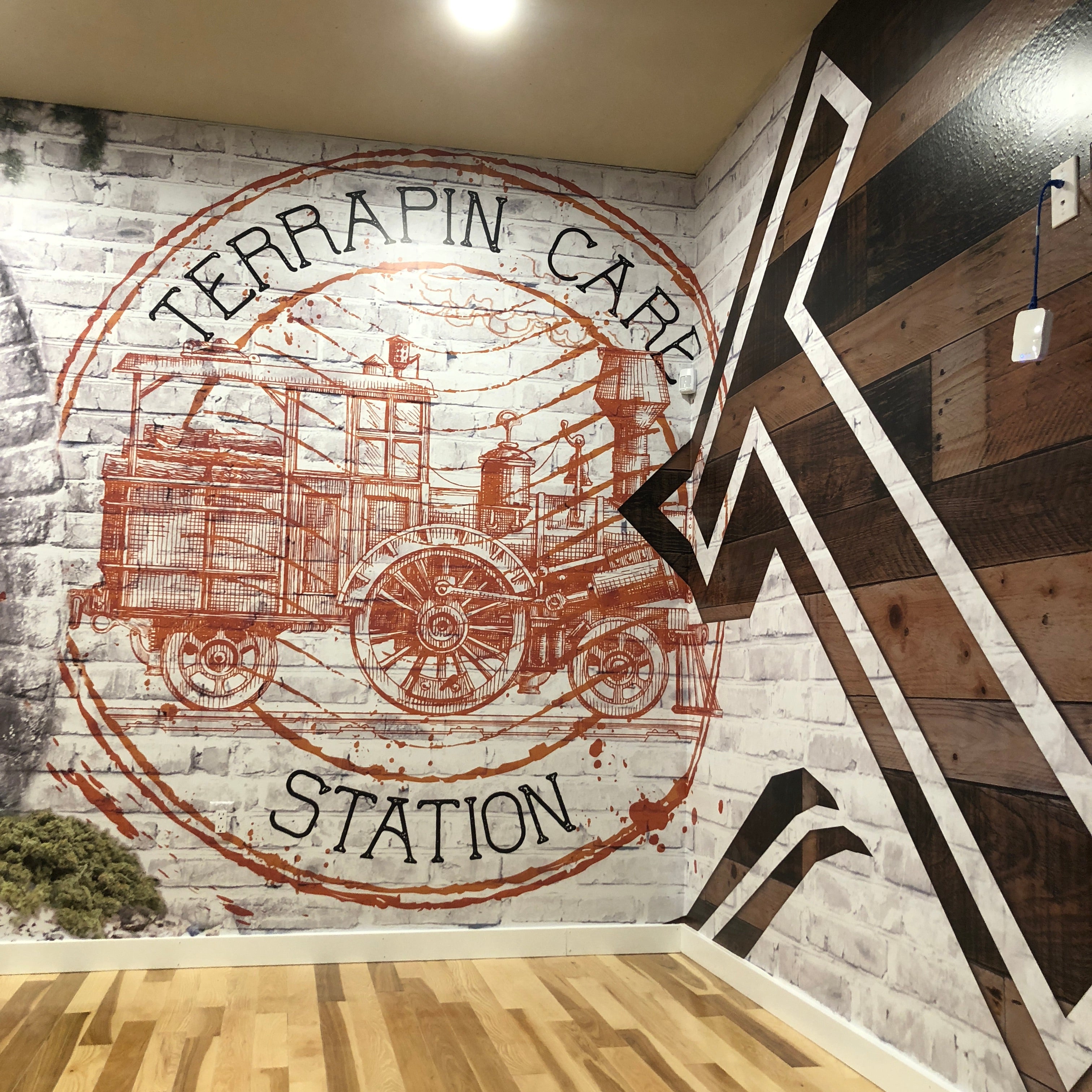 An interior wall wrap for Terrapin Care Station in Longmont, Colorado, showcasing a rustic design with a vintage train graphic and wood-patterned elements, enhancing the ambiance of the space.