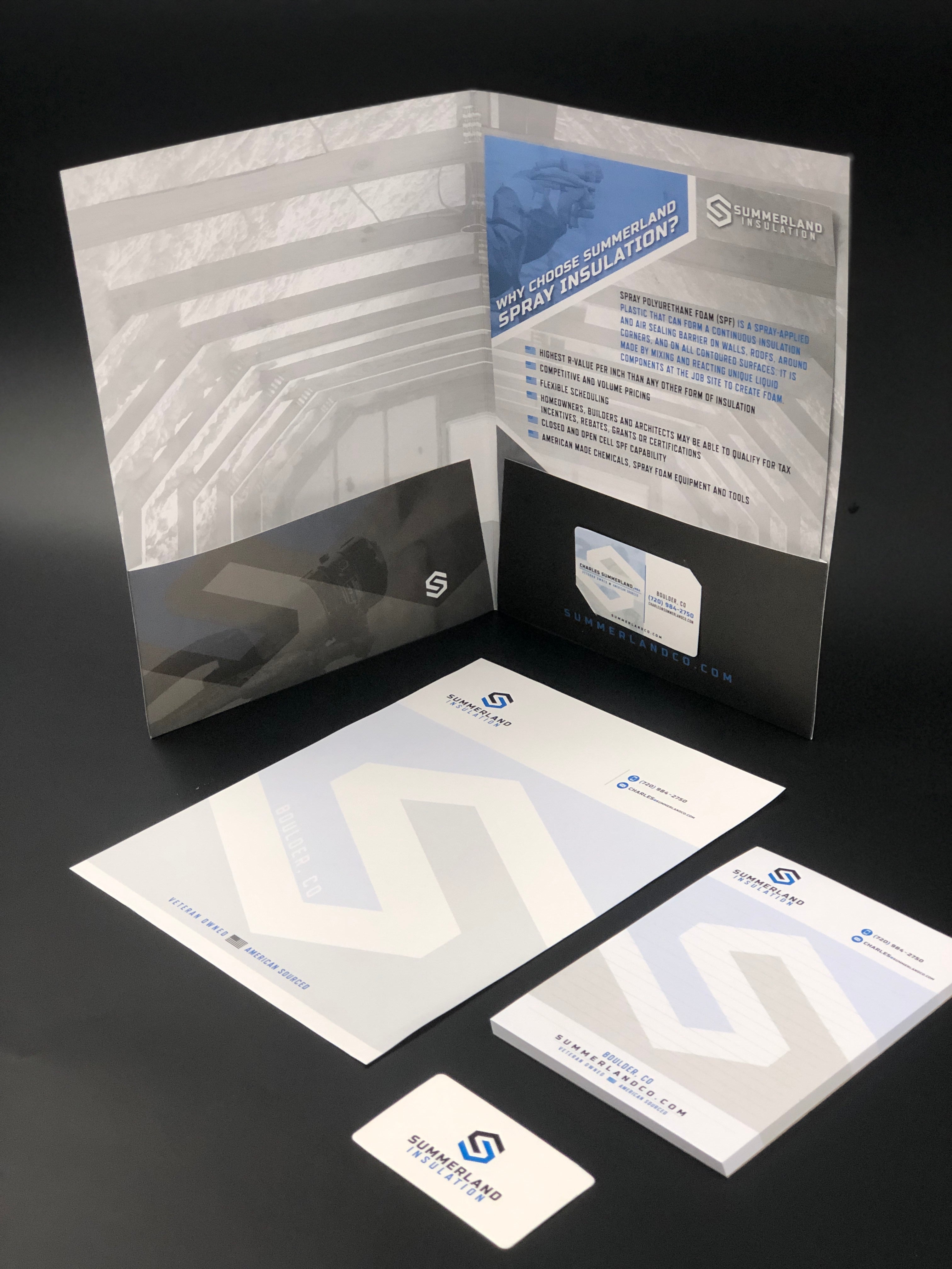 A neatly arranged display of brand guidelines for Summerland Installations, based in Boulder, Colorado. The set includes a folder, letterhead, notepad, and business card, all featuring the company's sleek, modern logo and design elements in a blue and gray color scheme.