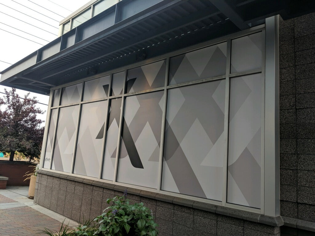 Exterior window wrap for an Xfinity Store by Comcast, featuring a sleek geometric design in shades of grey. Located in Westminster, Colorado.