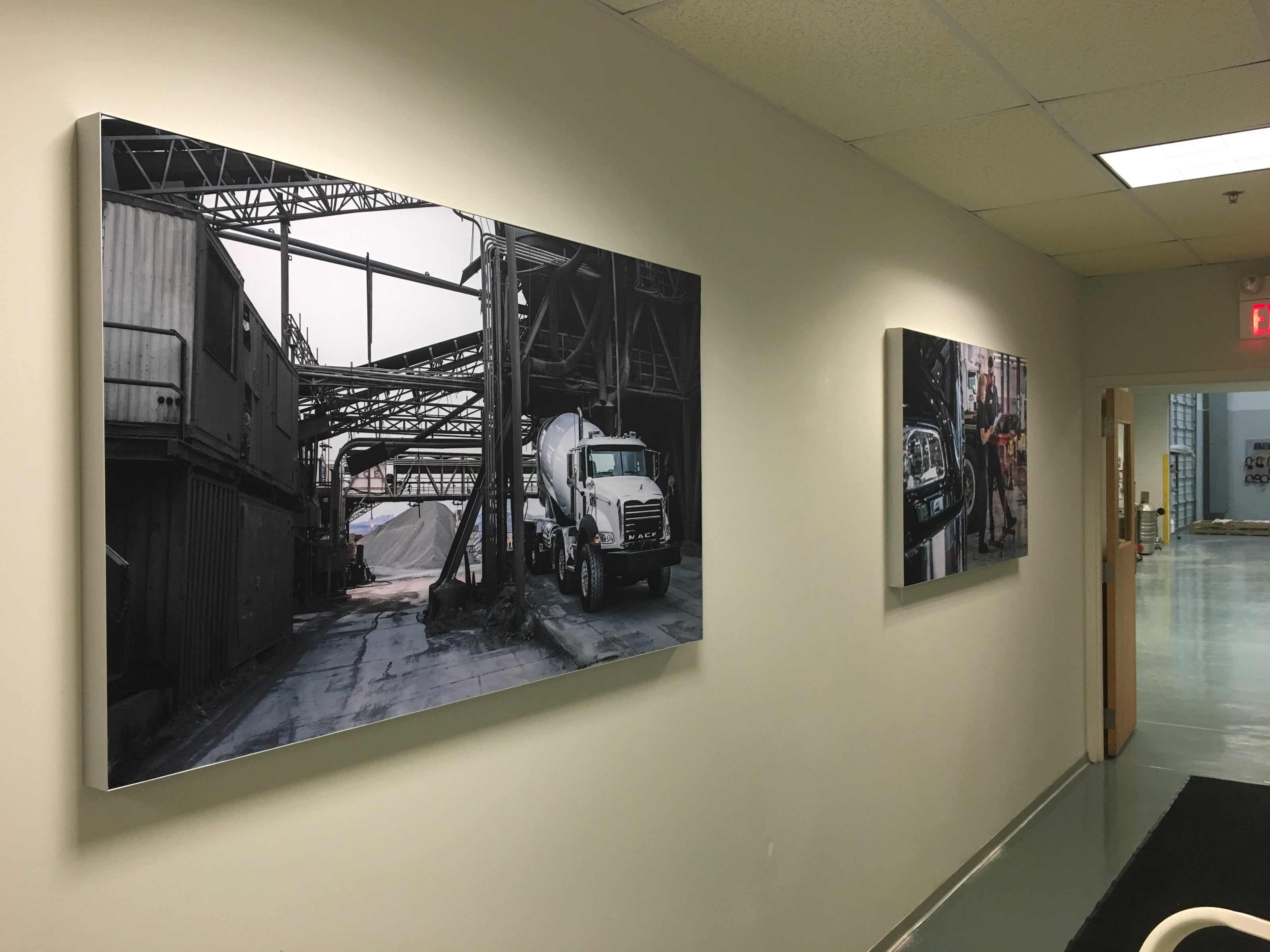 Silicone Edge Graphics (SEG) fabric frames displayed in a hallway at Volvo Mack in Atlanta, Georgia, showcasing industrial-themed black-and-white photos of trucks and construction environments.