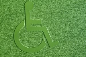 ada sign 300x200 - Disabled symbol on a green textured background.